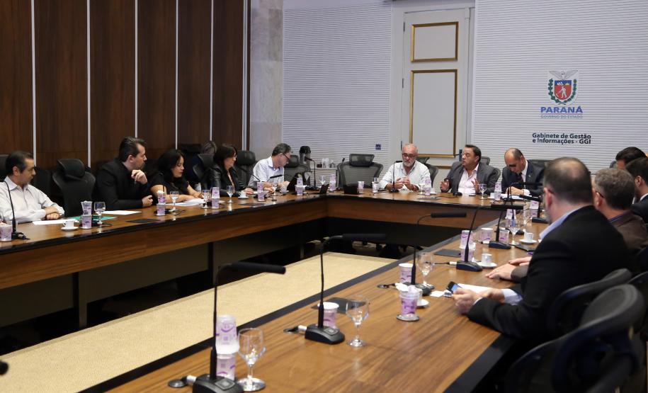 Foto dos participantes na mesa de reunião.