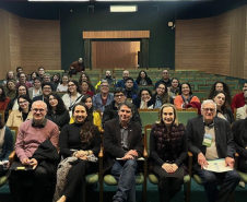 Público e palestrantes sorrindo e olhando para a câmera.