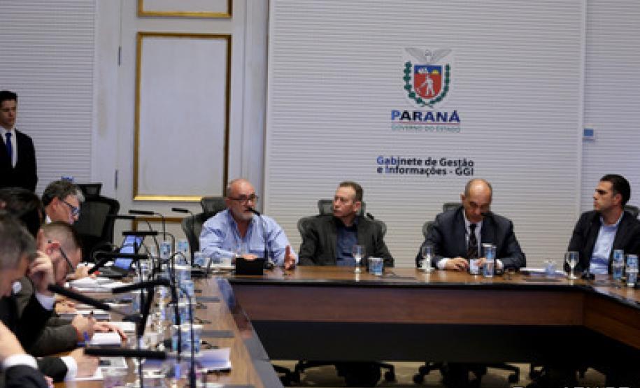 Foto dos participantes na mesa de reunião.