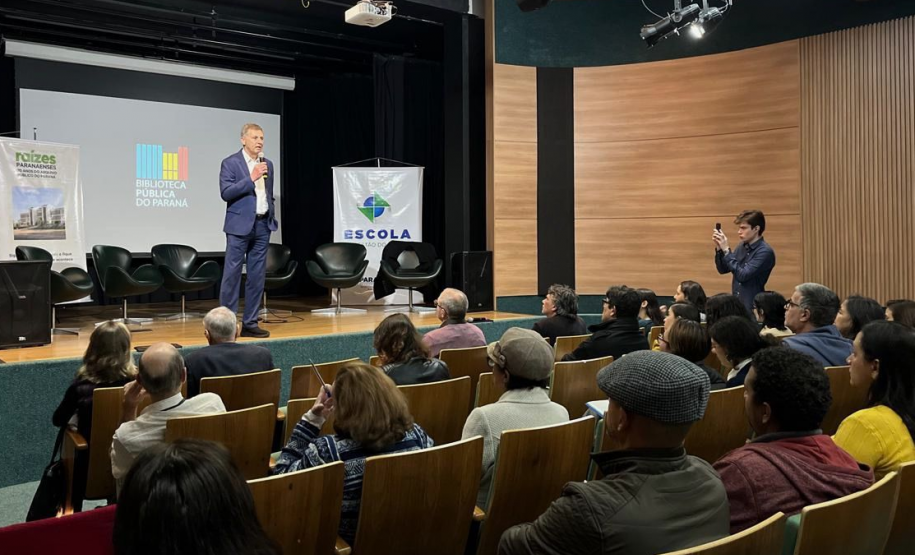 Público sentado em auditório assiste secretário Luizão Goulart, que está em cima de um palco.